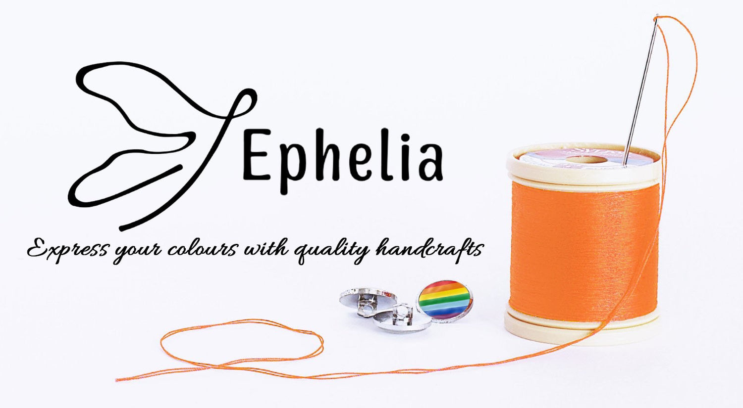 Το logo του brand Εphelia σε λευκό φόντο και απο κάτω η φράση "Express your colours with quality handcrafts" με καλλιτεχνικά γράμματα. Δίπλα μία λευκή κουβαρίστρα με πορτοκαλί κλωστή , στη κορυφή της μια βελόνα με περασμένη πορτοκαλί κλωστή και 3 κουμπιά. Τα δύο ασημί και το ένα με χρώμα rainbow.