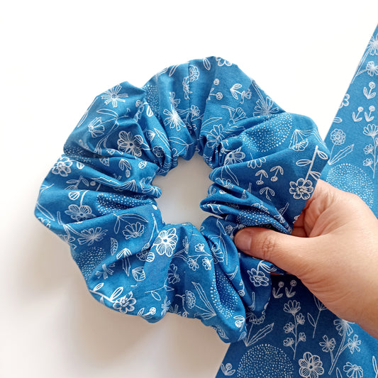 Λαστιχάκι scrunchie μεγάλου μεγέθους σε μπλε χρώμα με σχέδιο λευκά περιγράμματα λουλουδιών.